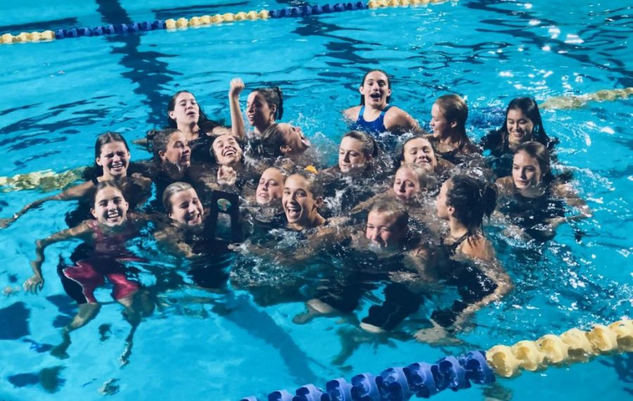 The Academy swim team continues their tradition of jumping into the pool with their trophy after earning the title of regional champions.