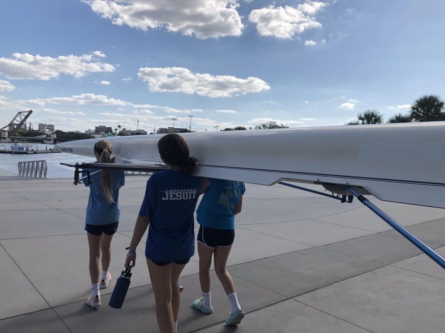 Long boats are carried out by multiple girls to be put in the water.