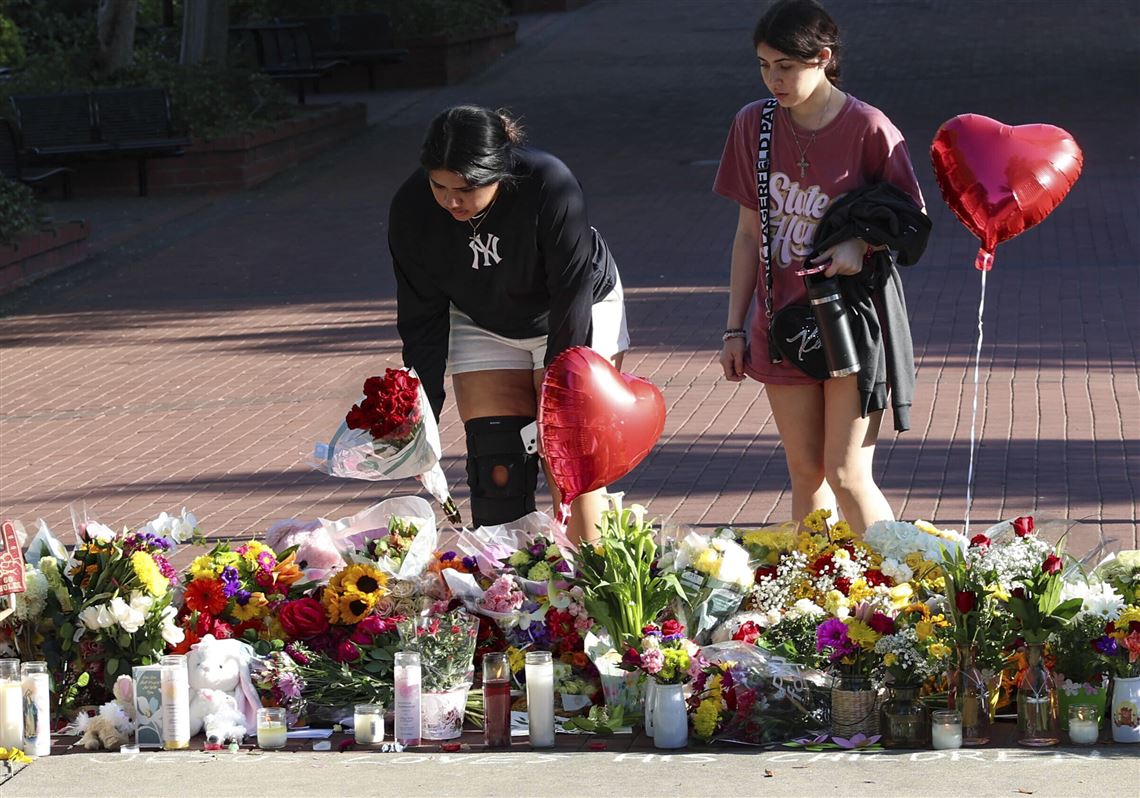 students creating a pile of flowers and candles to send their prayers.